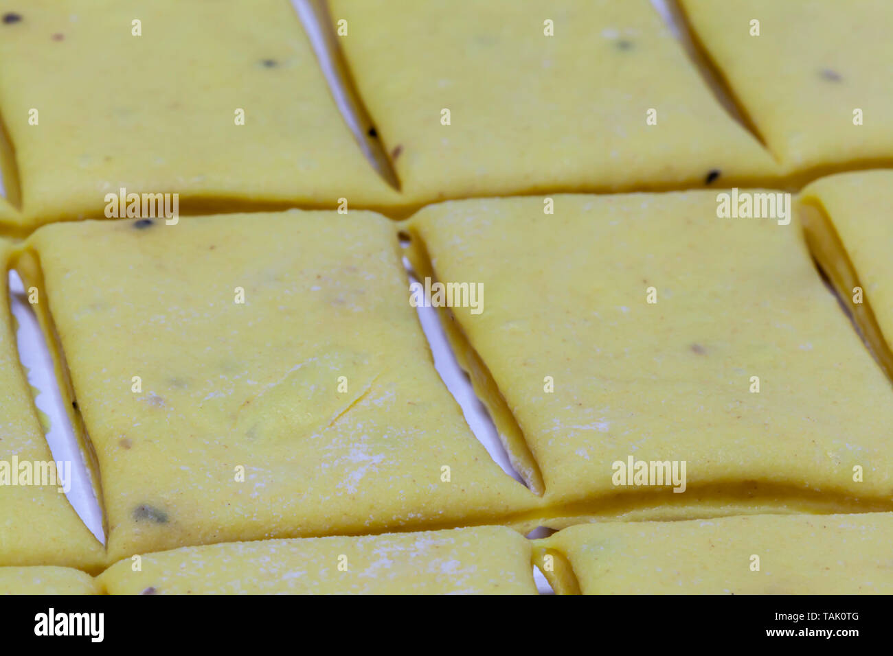 Homemade dumpling dough cut into rectangles on wax paper to be placed in a pot of chicken and chicken broth for chicken and dumplings. Stock Photo