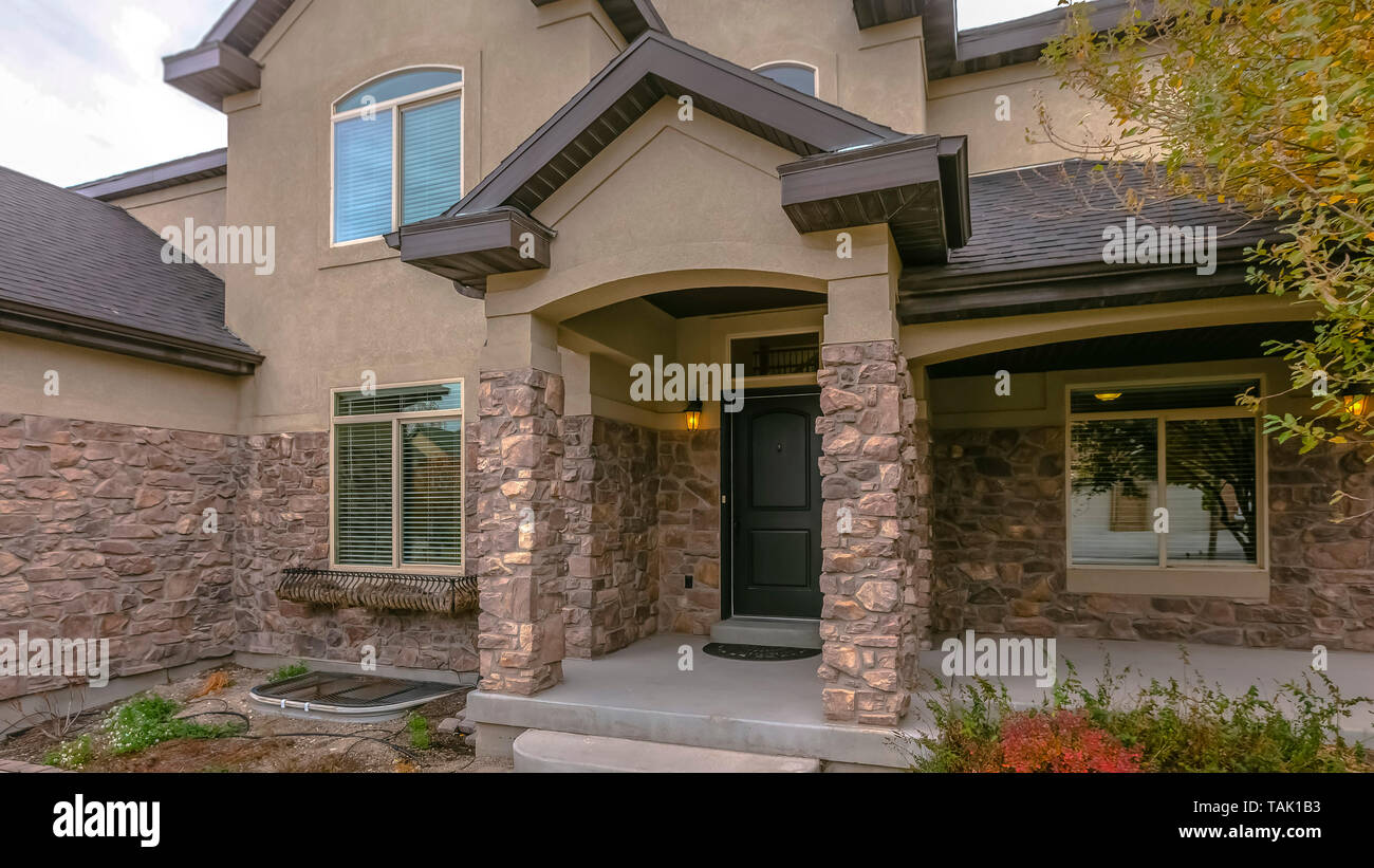 Facade Of A Home With Stone Wall And Welcoming Covered Front Porch Lush Plants And Trees Thrive On The Landscaped Garden Of This House Stock Photo Alamy