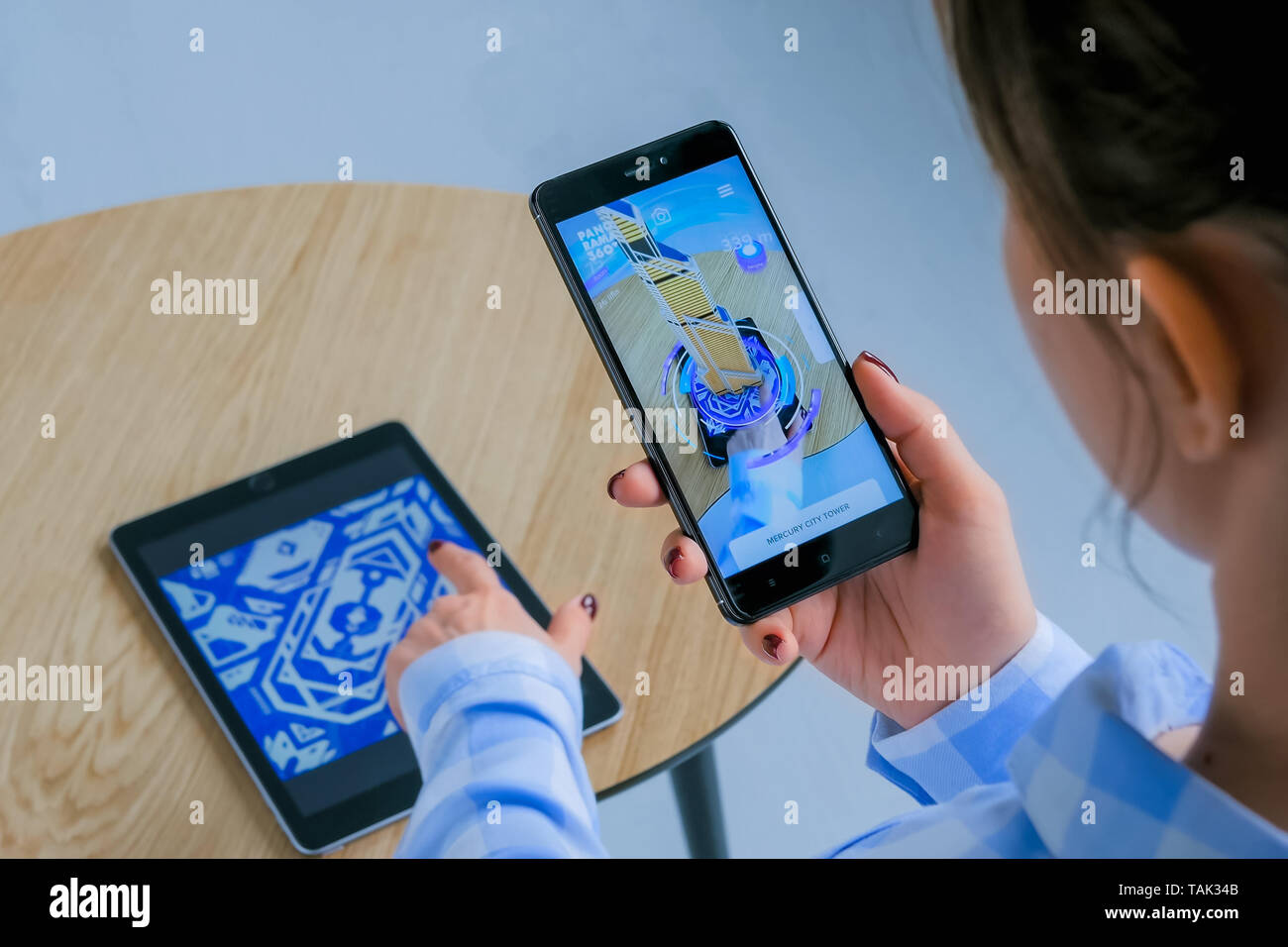 Woman using smartphone with AR app and placing virtual model of building Stock Photo
