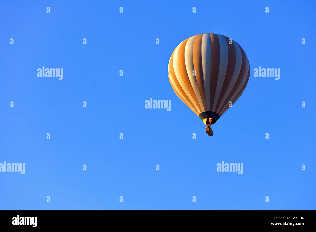 The flame of fire heats the air in a motley yellow-white beautiful balloon  and raises a basket of tourists to the blue sky Stock Photo - Alamy