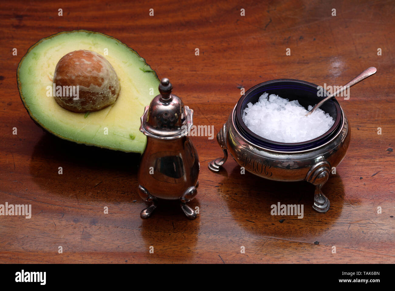 Avocado cut in half on a plain wooden table Stock Photo - Alamy