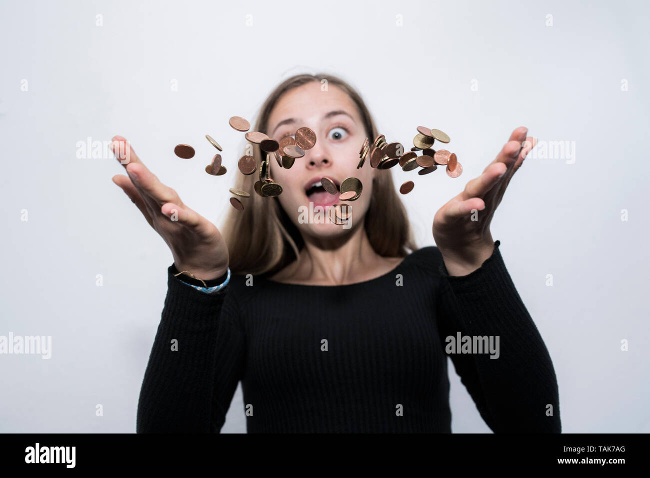 Teenage girl throwing money coins in the air. Stock Photo