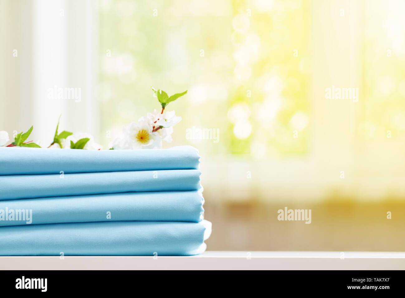 Closeup stack of blue clean bedding on the table. Blurred background. Copy space. Stock Photo