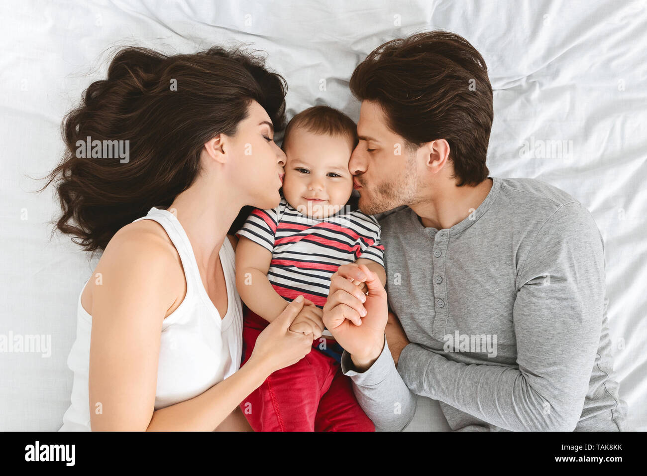Mother and father kissing their adorable baby Stock Photo - Alamy