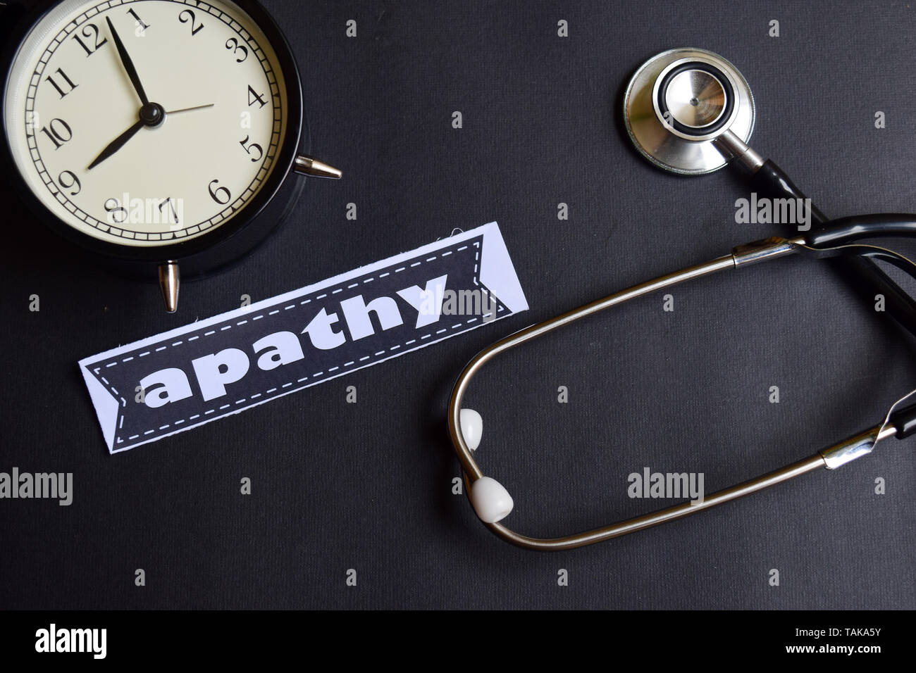 Apathy on the paper with Healthcare Concept Inspiration. alarm clock, Black stethoscope. Stock Photo
