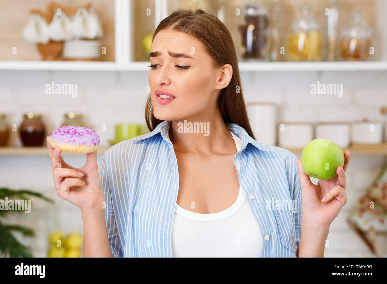 Hard Choice. Woman Choosing Between Apple And Donut Stock Photo