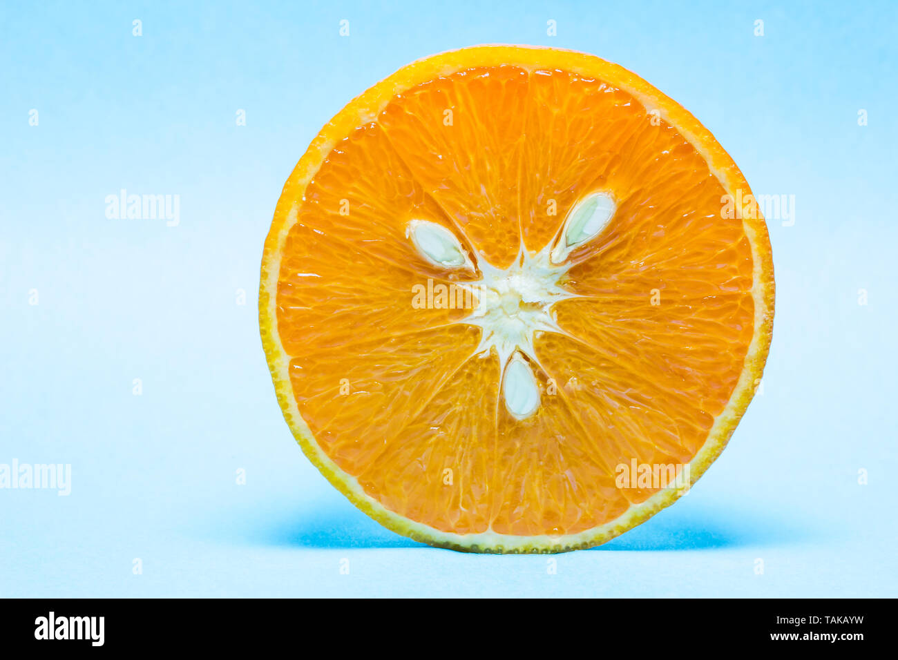 Fresh and ripe orange with seeds on light blue background. Stock Photo