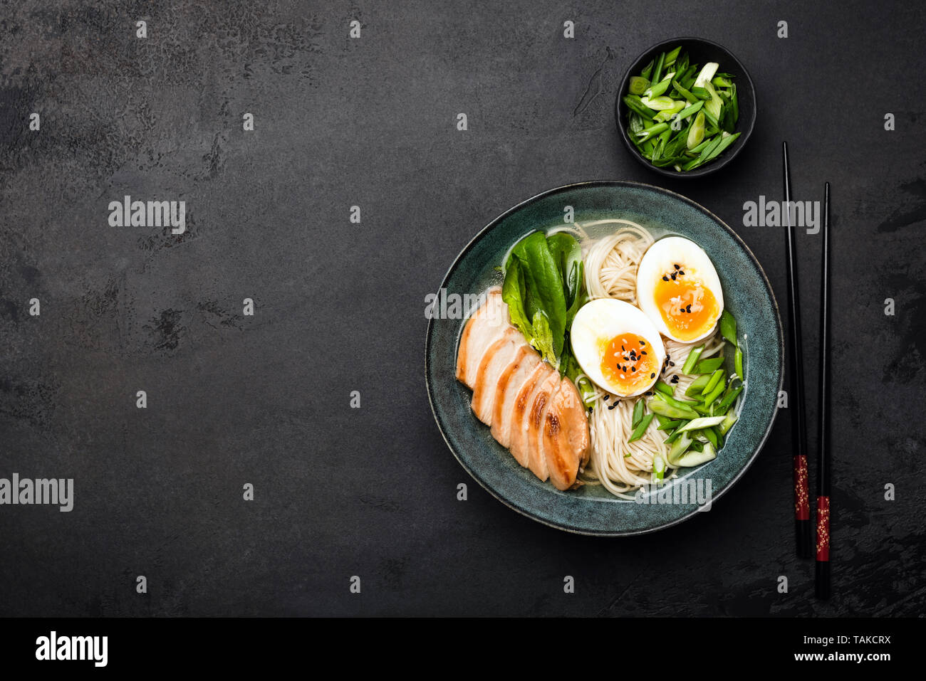 Asian ramen noodle soup with chicken on black concrete background. Top view, copy space for text Stock Photo
