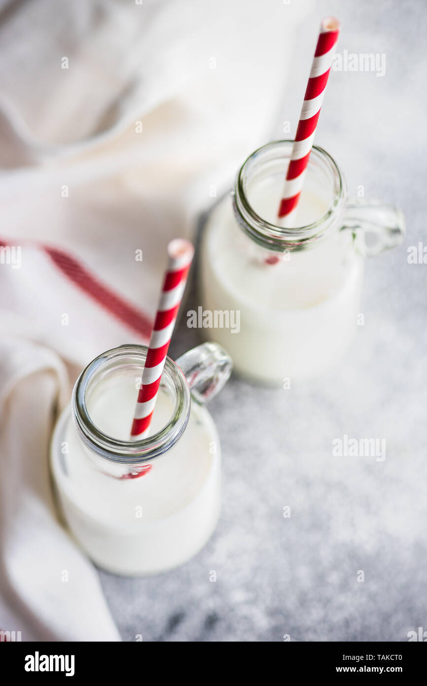 Milk in vintage bottles with stripped red and white straws on grey concrete  table with copyspace Stock Photo