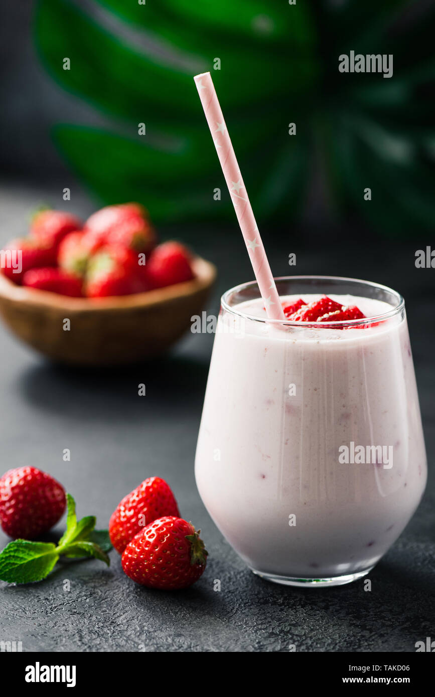 Healthy strawberry smoothie milkshake in glass with pink drinking straw ...