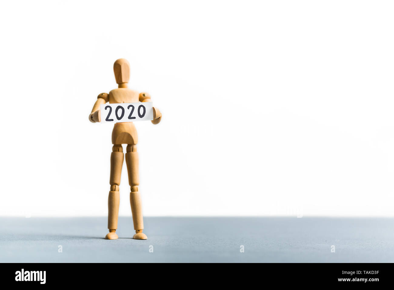 Wooden mannequin holding 2020 year sign in hands Stock Photo
