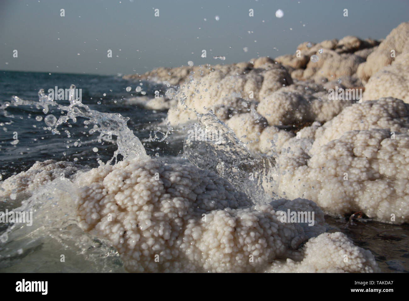 Water splashes over crystallised salt rocks at The Dead Sea in Jordan