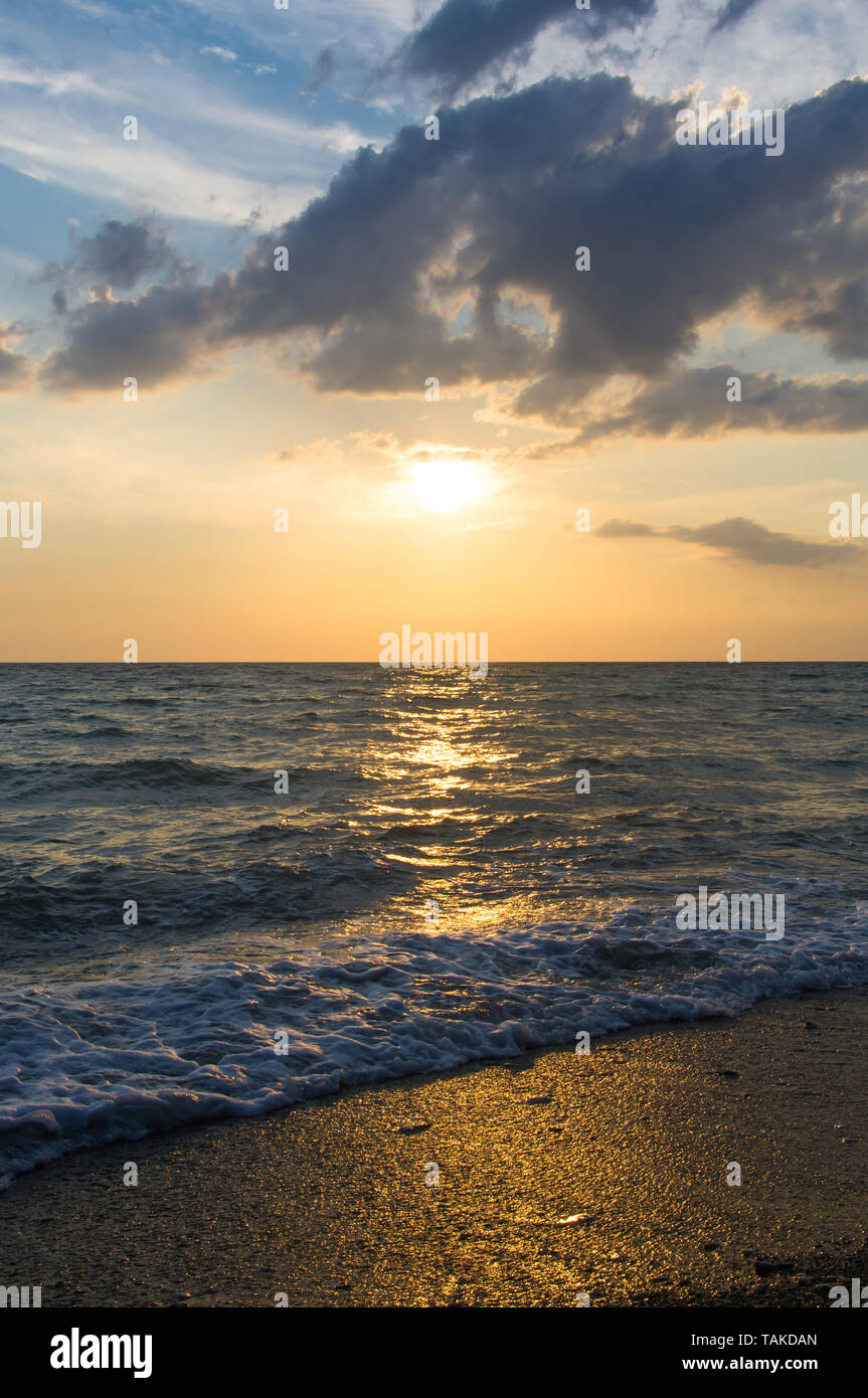 Summer sea sunset on the pebble beach, the sun, waves and clouds ...