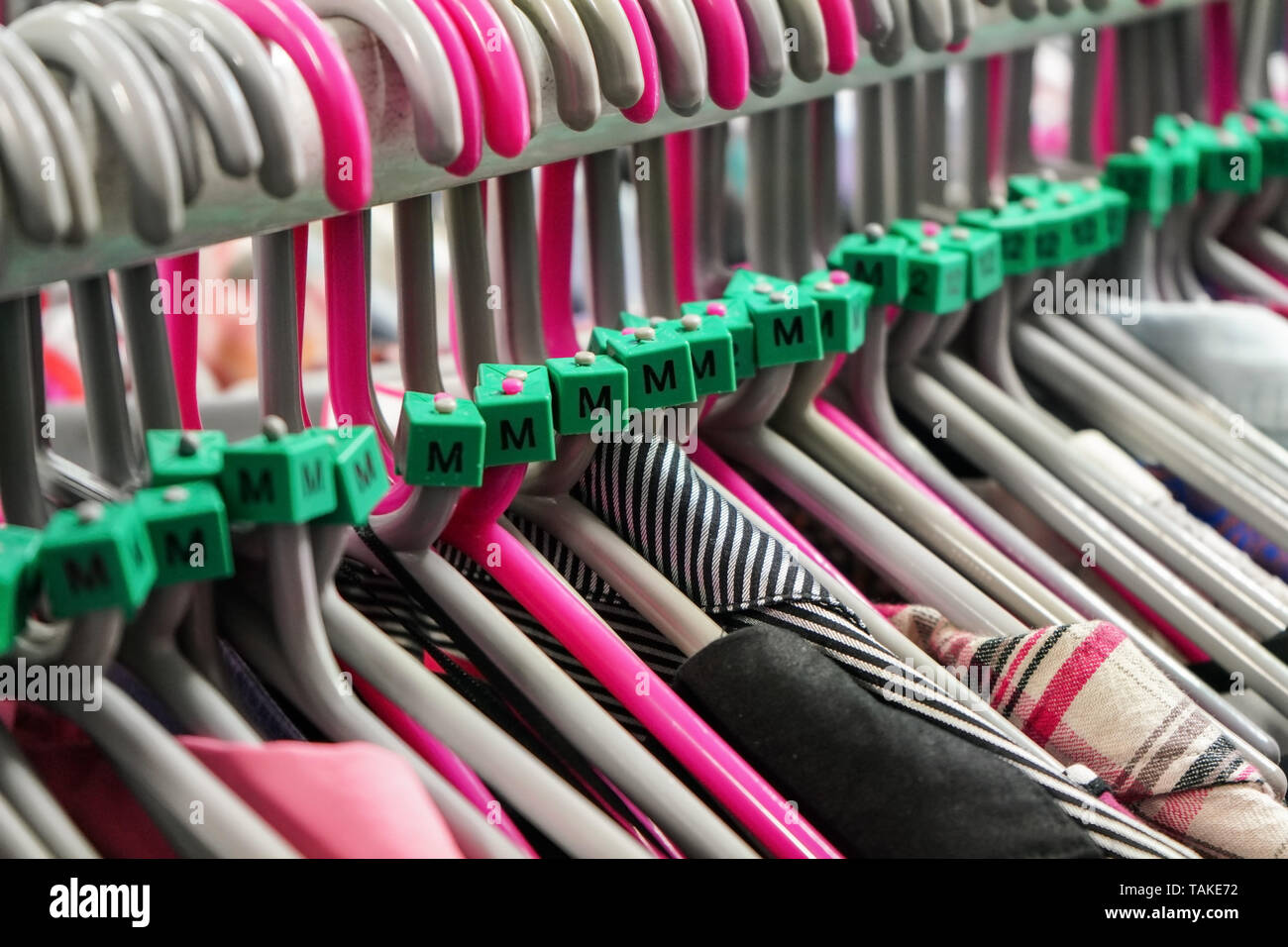 Cloth hangers with various women clothing in thrift shop, detail on M