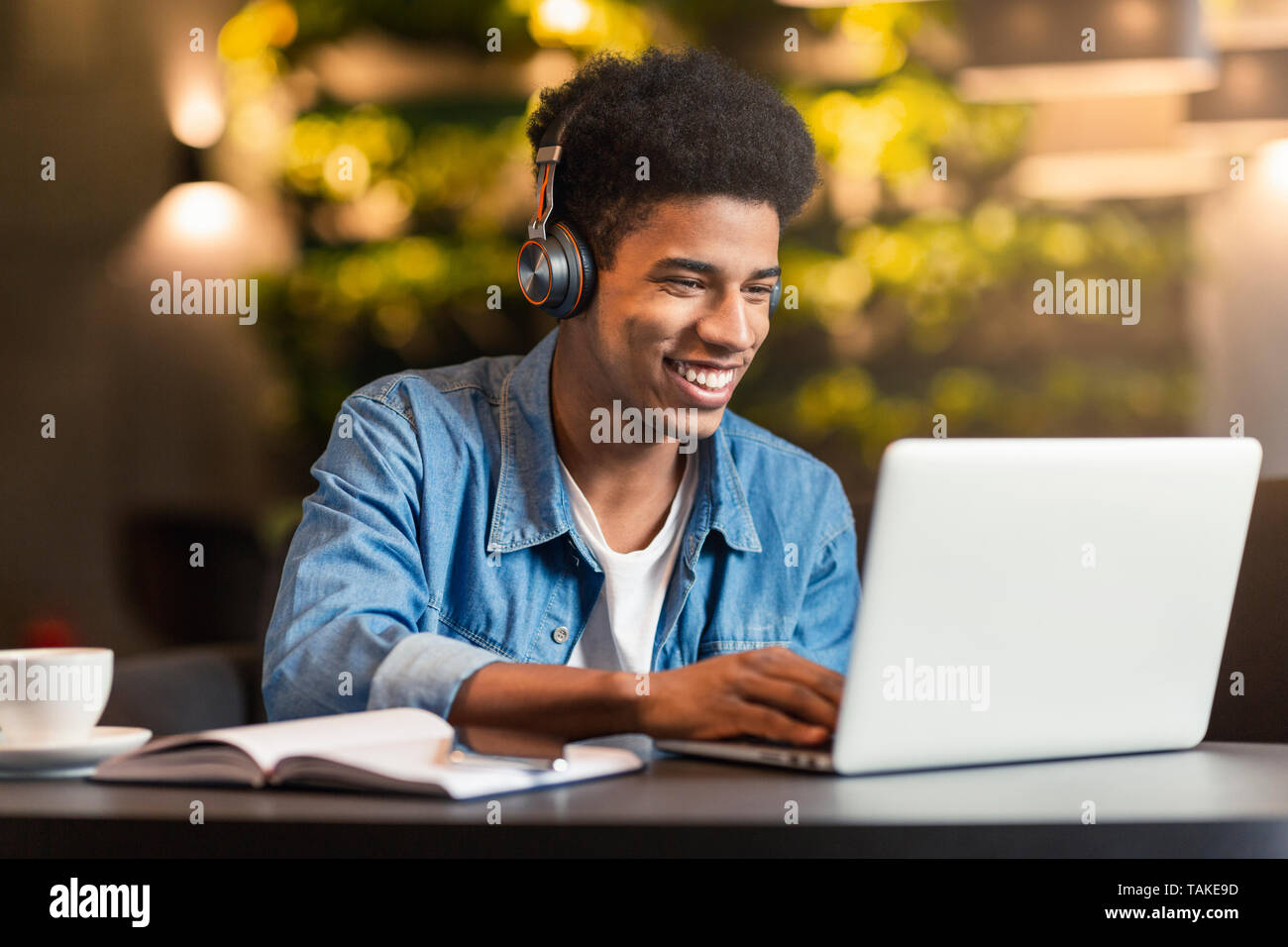 Black Teen Gamer Playing in Video Game on Laptop in Cafe Stock Photo