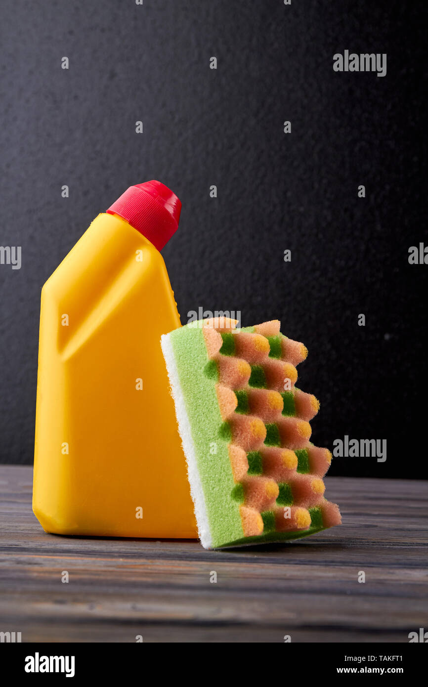 Detergent in yellow bottle and sponge. Plastic bottle with cleaning