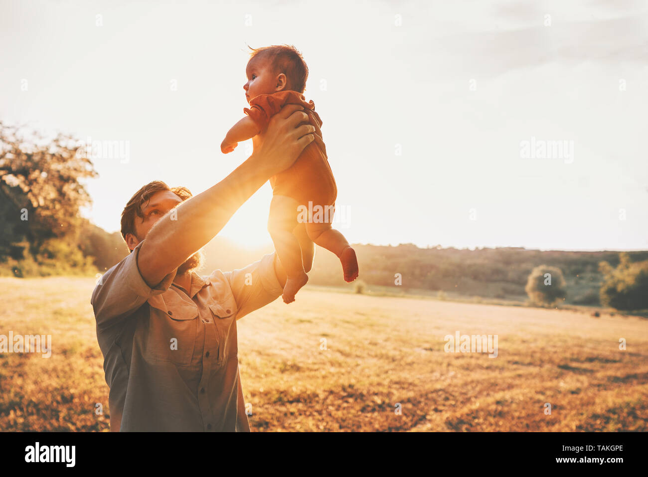 Father holding baby up in the air playing together family lifestyle daddy and child walking outdoor parenthood concept Fathers day holiday Stock Photo