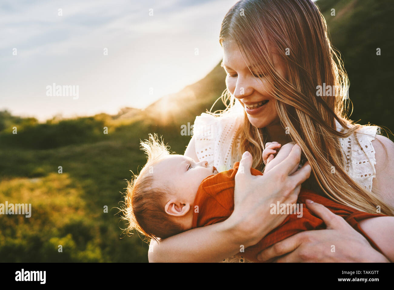 Happy mother walking with infant baby outdoor family lifestyle mom holding child maternity Mothers day summer travel vacations Stock Photo