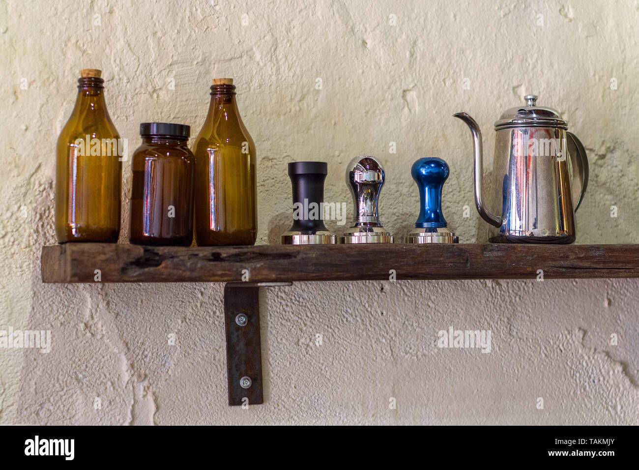 https://c8.alamy.com/comp/TAKMJY/coffee-tamper-and-gooseneck-kettle-on-display-on-a-wooden-shelf-on-a-coffee-chop-wall-TAKMJY.jpg