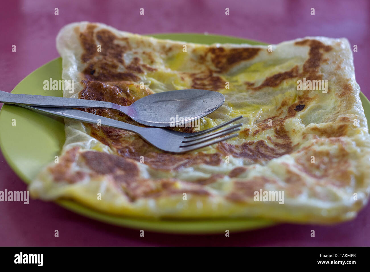 Basic asian pancake severed on a green plate with spoon and fork. Stock Photo