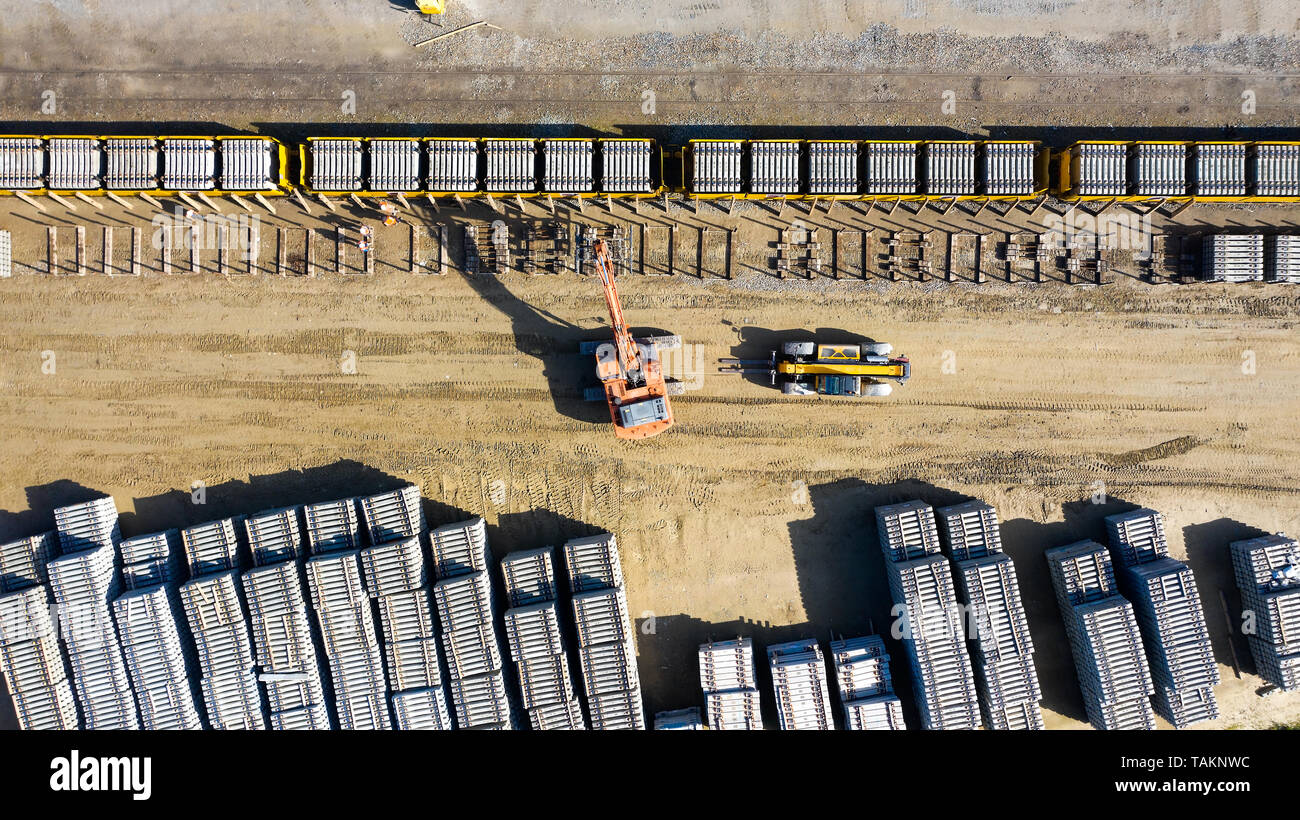 Heavy machines loading concrete railway sleepers on a train Stock Photo