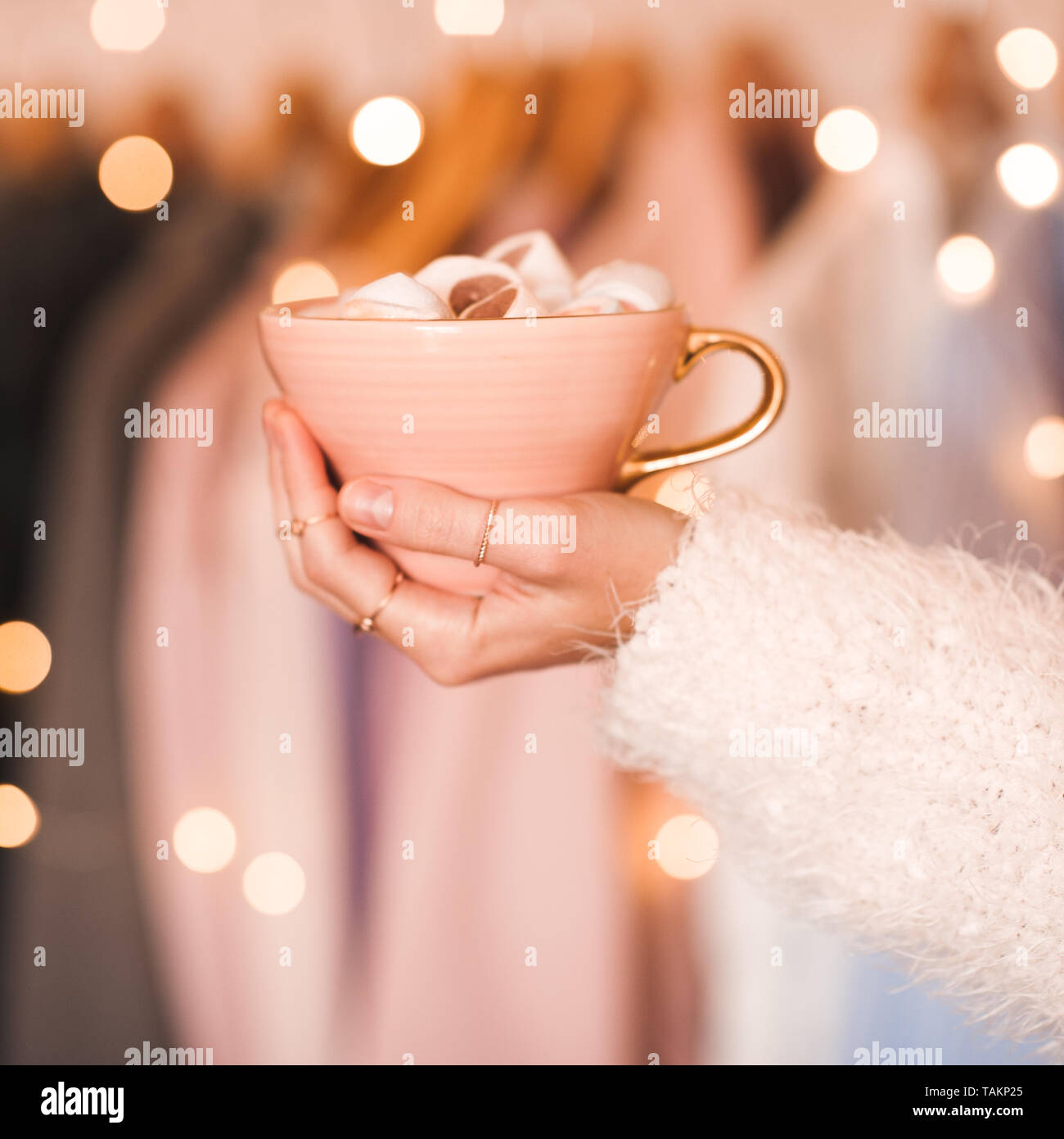Girl holding cup of coffee over Christmas lights closeup. Good morning. Stock Photo