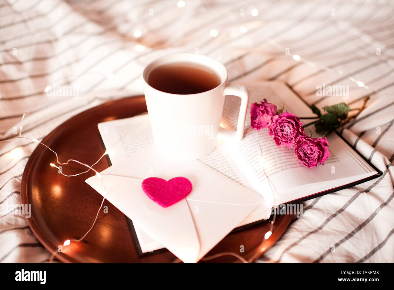 Romantic morning with cup of tea staying on open book with flowers ...