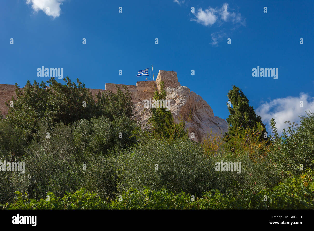 Acropolis Walls of Athens viewed from below with trees and Greek flag ...