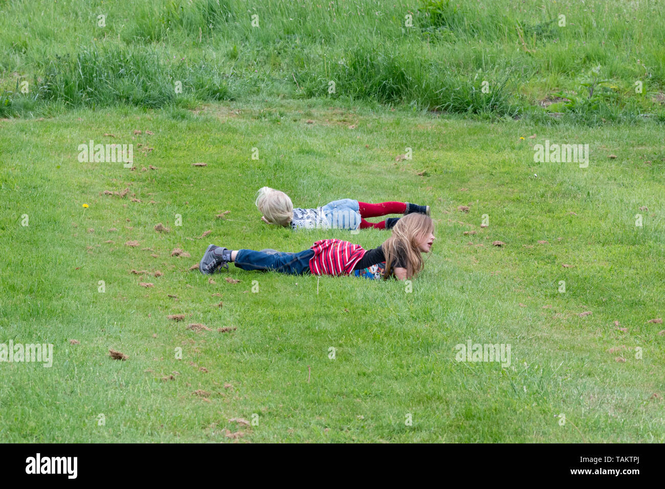 Kids Having Fun Rolling Down A Grassy Hill Stock Photo, Picture