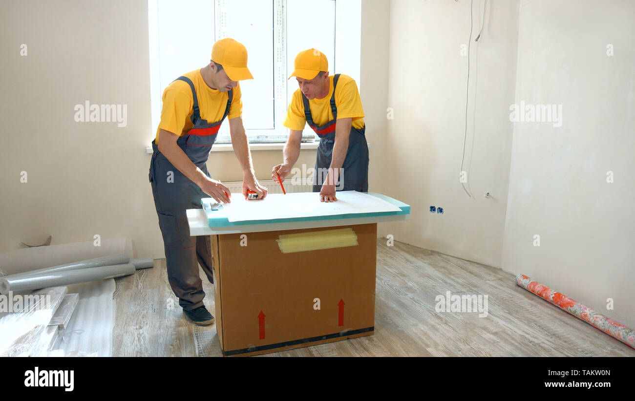 ?onfident builders looking at building plan at construction site. Two professional builders looking at plan of building indoors. Stock Photo