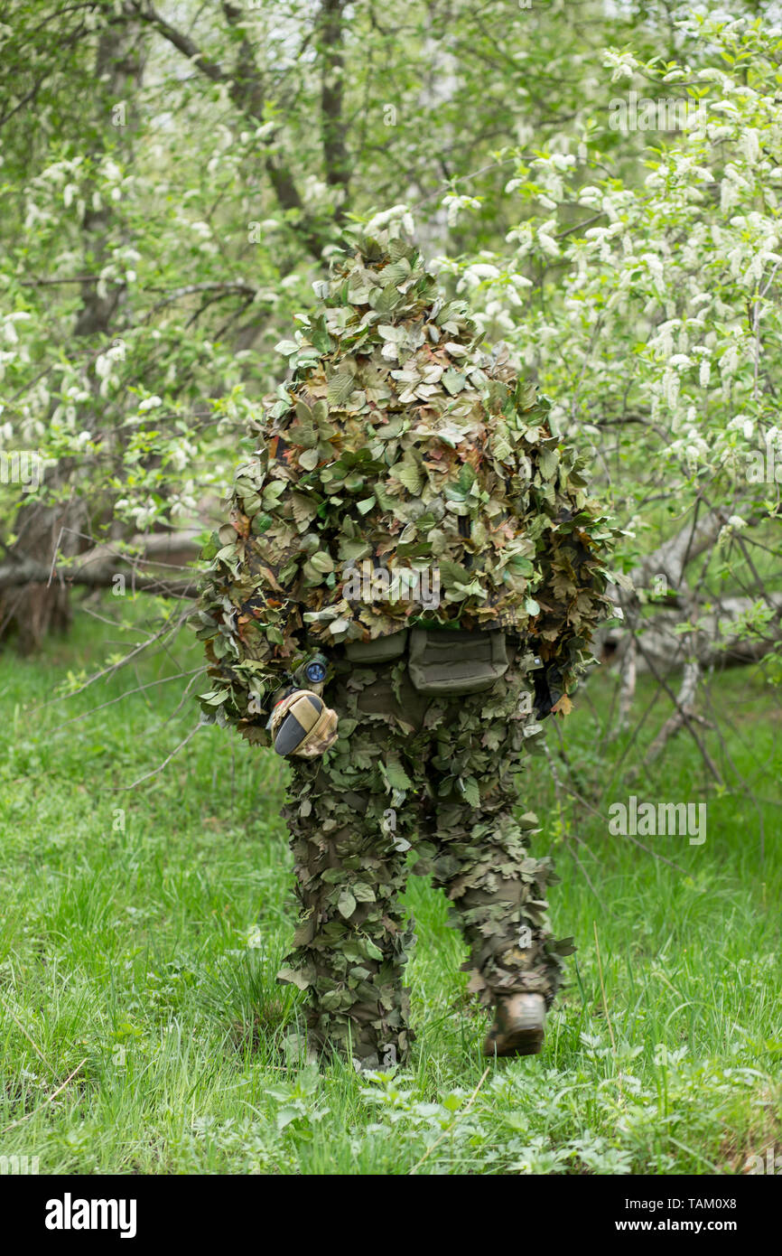 Sniper in green camouflage camouflage clothing in the forest goes back.  Army, military, airsoft, hobby, game concept Stock Photo - Alamy