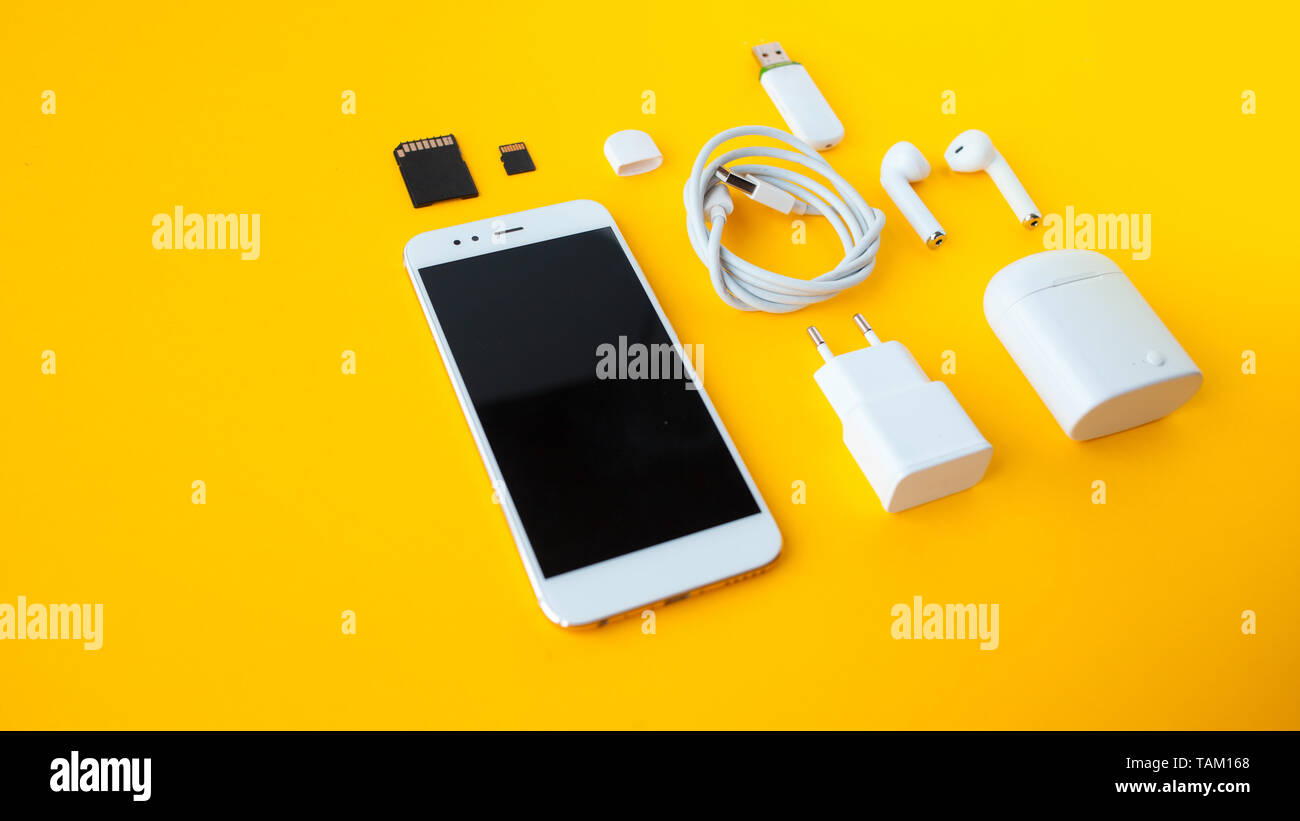Mobile kit with smartphone, wireless headphones and chargers. Yellow ...