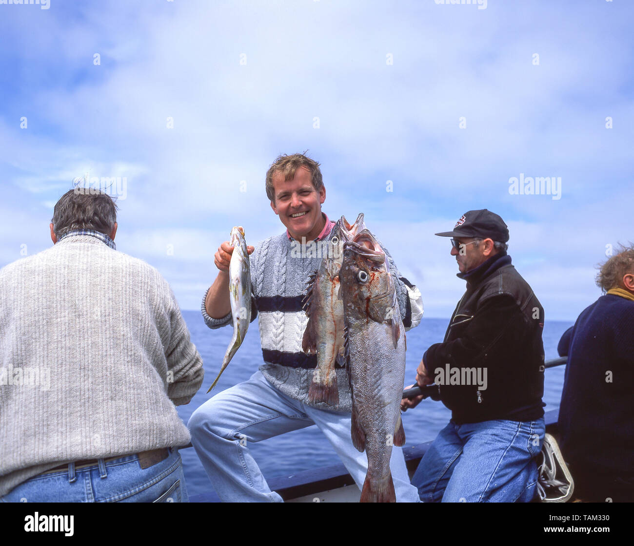 Young man holding fish catch on fishing boat, Oamaru, Otago Region, South Island, New Zealand Stock Photo