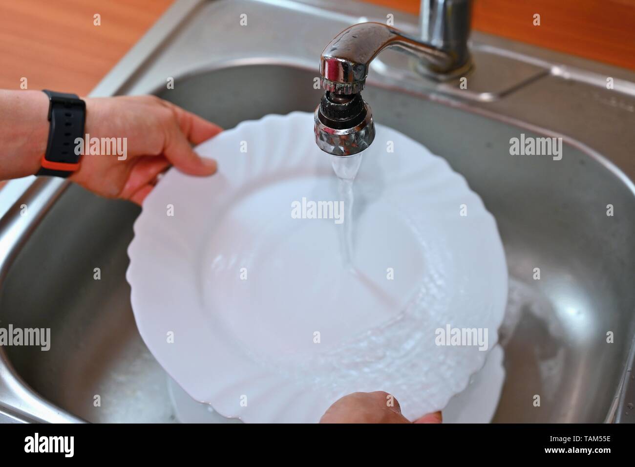 Hand washing dishes. Hand with sponge and sink in kitchen washing dirty
