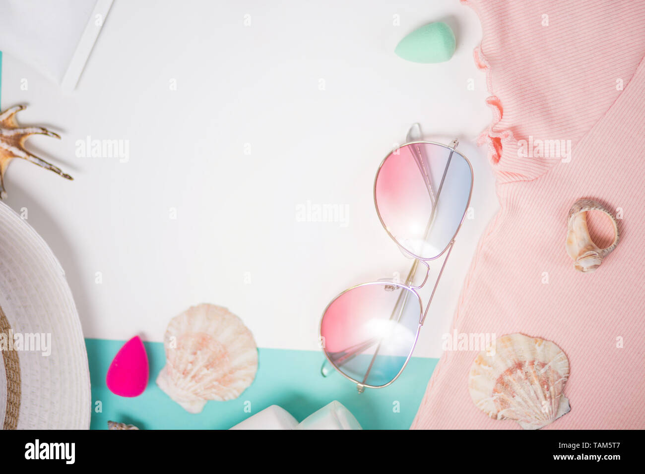 Flat lay composition with sunglasses, seashells, sunblock, pink t shirt, straw hat. Beach accessories on white light blue background. Summer, vacation Stock Photo