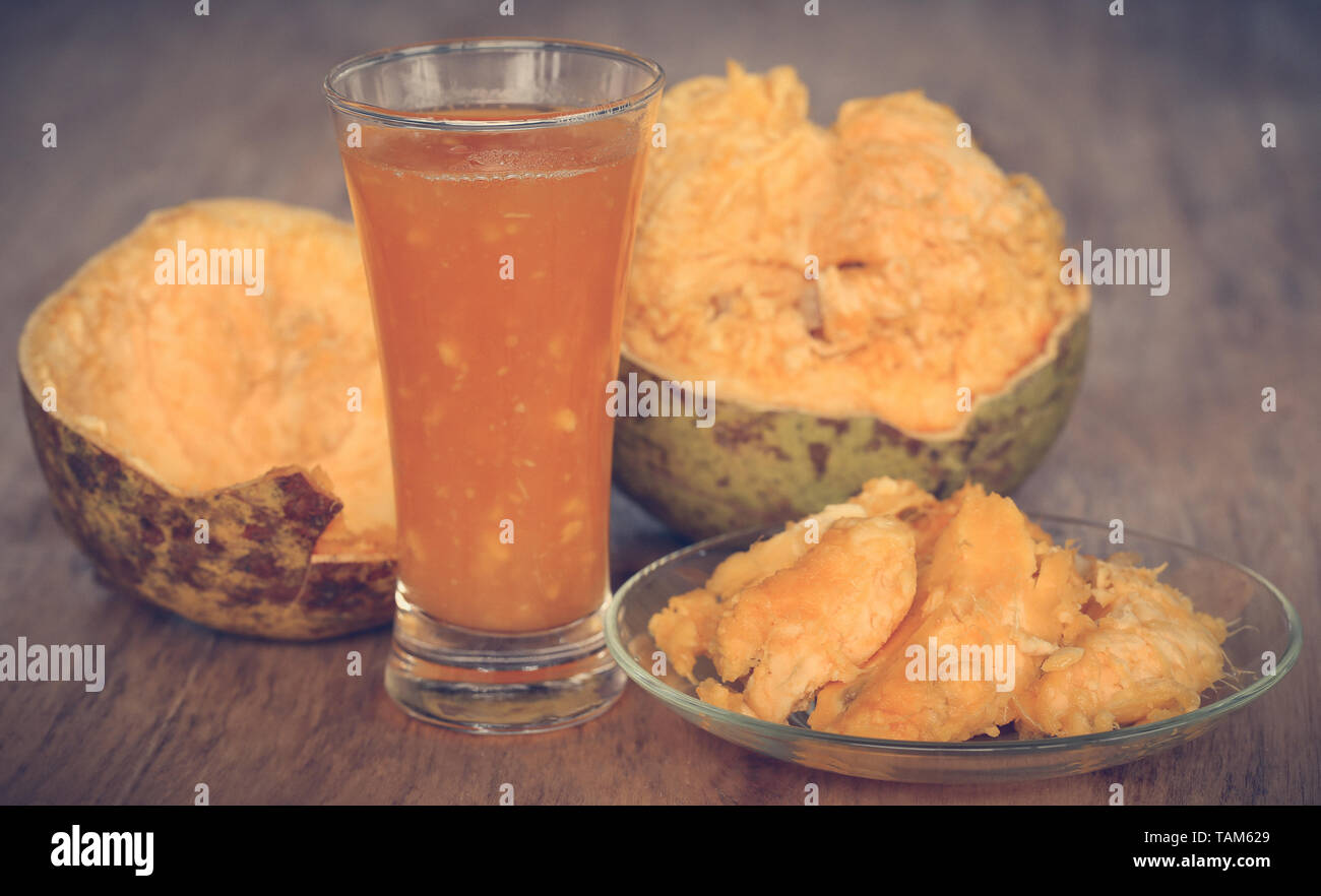 Medicinal Bael fruit with juice in a glass on wooden surface Stock Photo
