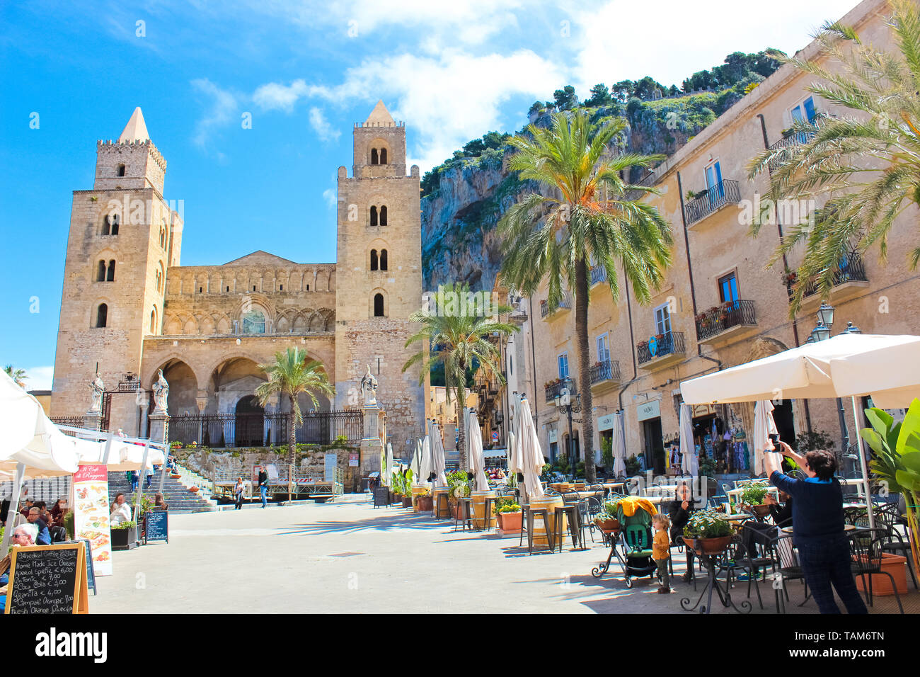 Cefalu, Sicily, Italy - Apr 7th 2019: Tourists on the old town square in  the outdoor cafe