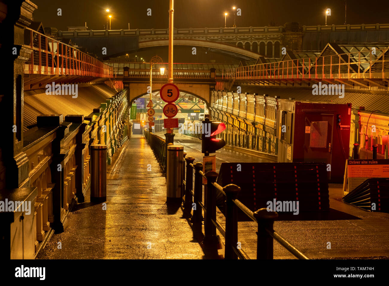 Footpath and road entrance leading underground to Waverley Railway station on a wet night, Edinburgh, Scotland, UK Stock Photo