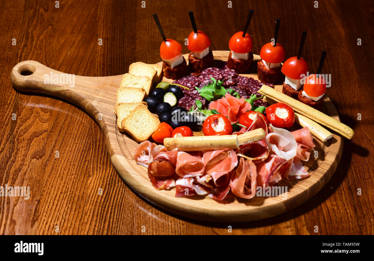 Antipasto platter. Cold meat plate with grissini bread sticks on wooden