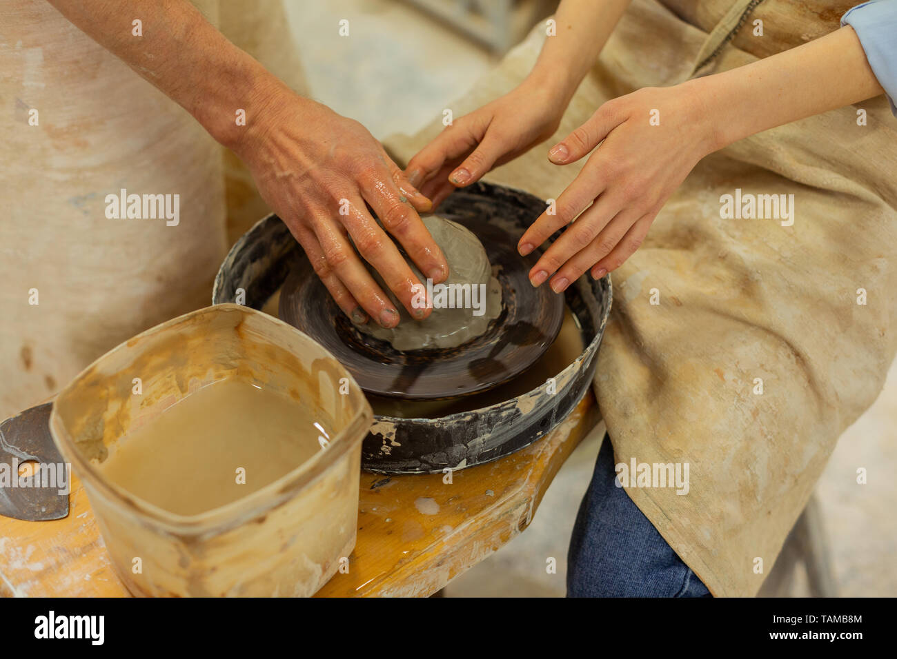 Pottery wheel technique. Girl in apron processing clay placed on