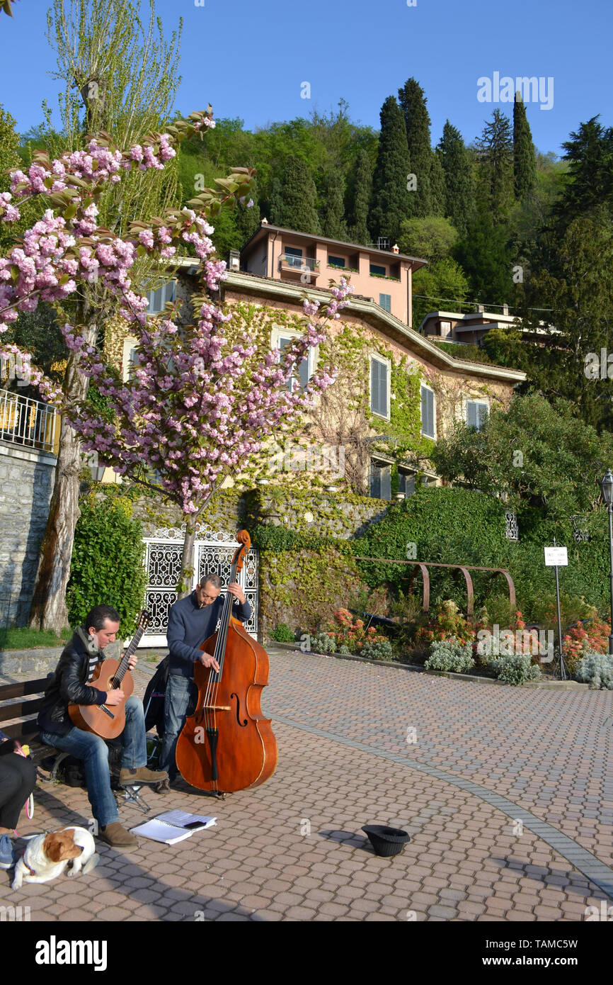 Two musicians playing classic guitar and contrabass at the Varenna lakefront in a sunny spring day. Stock Photo