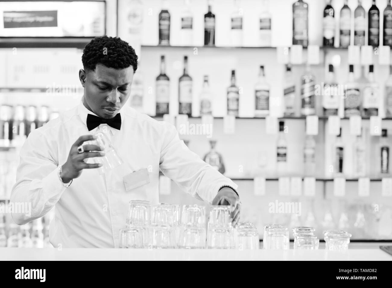 African american bartender wear on bow tie cleaning glasses at bar. Stock Photo
