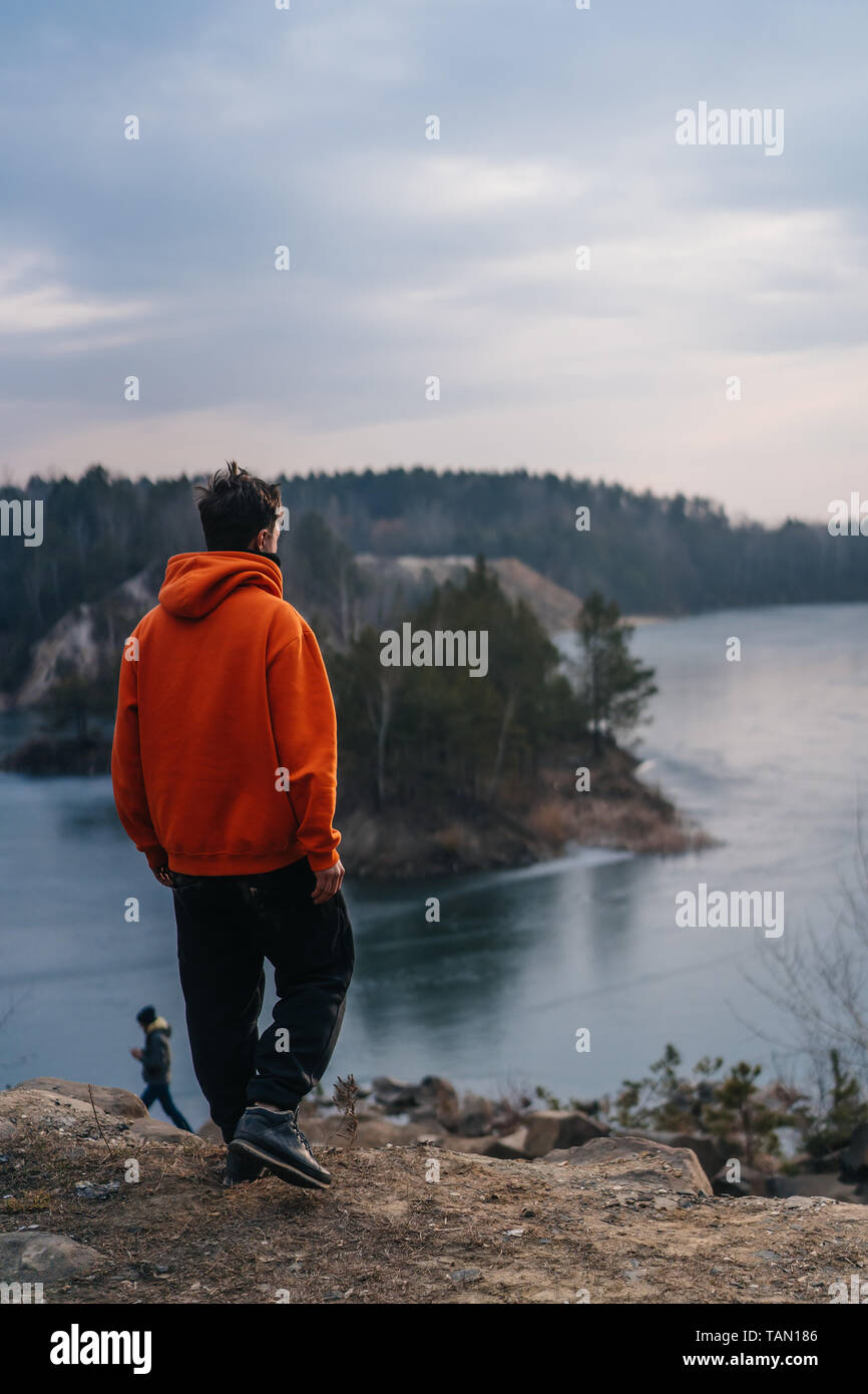 A young man standing on the edge of a cliff poses for the camera Stock ...