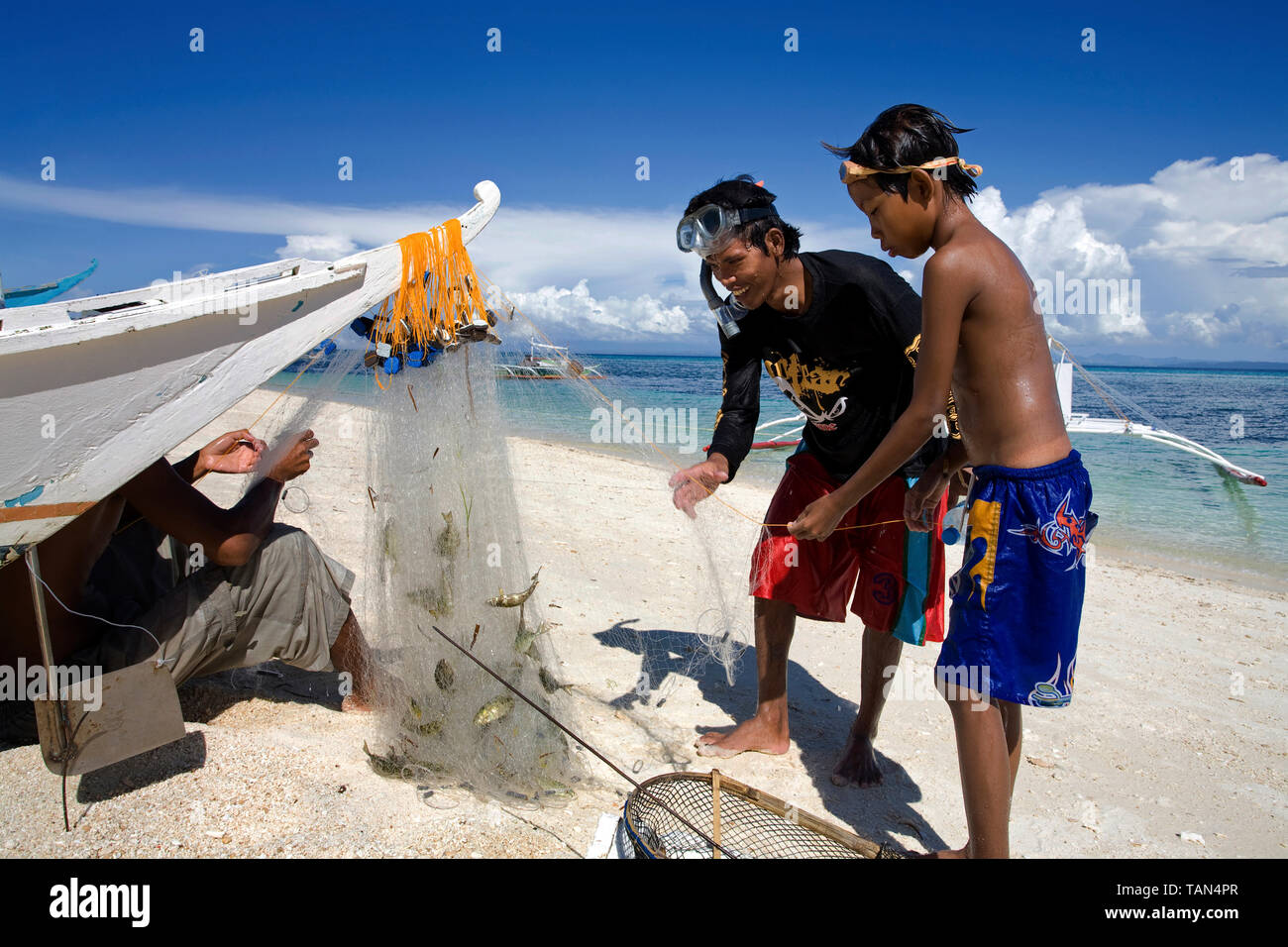 Fisherman takes the catch from the fishing net, Bounty beach, Malapascua island, Cebu, Philippines Stock Photo