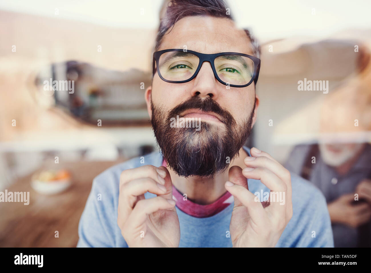 A portrait of a man standing indoors at home, shot through glass. Stock Photo
