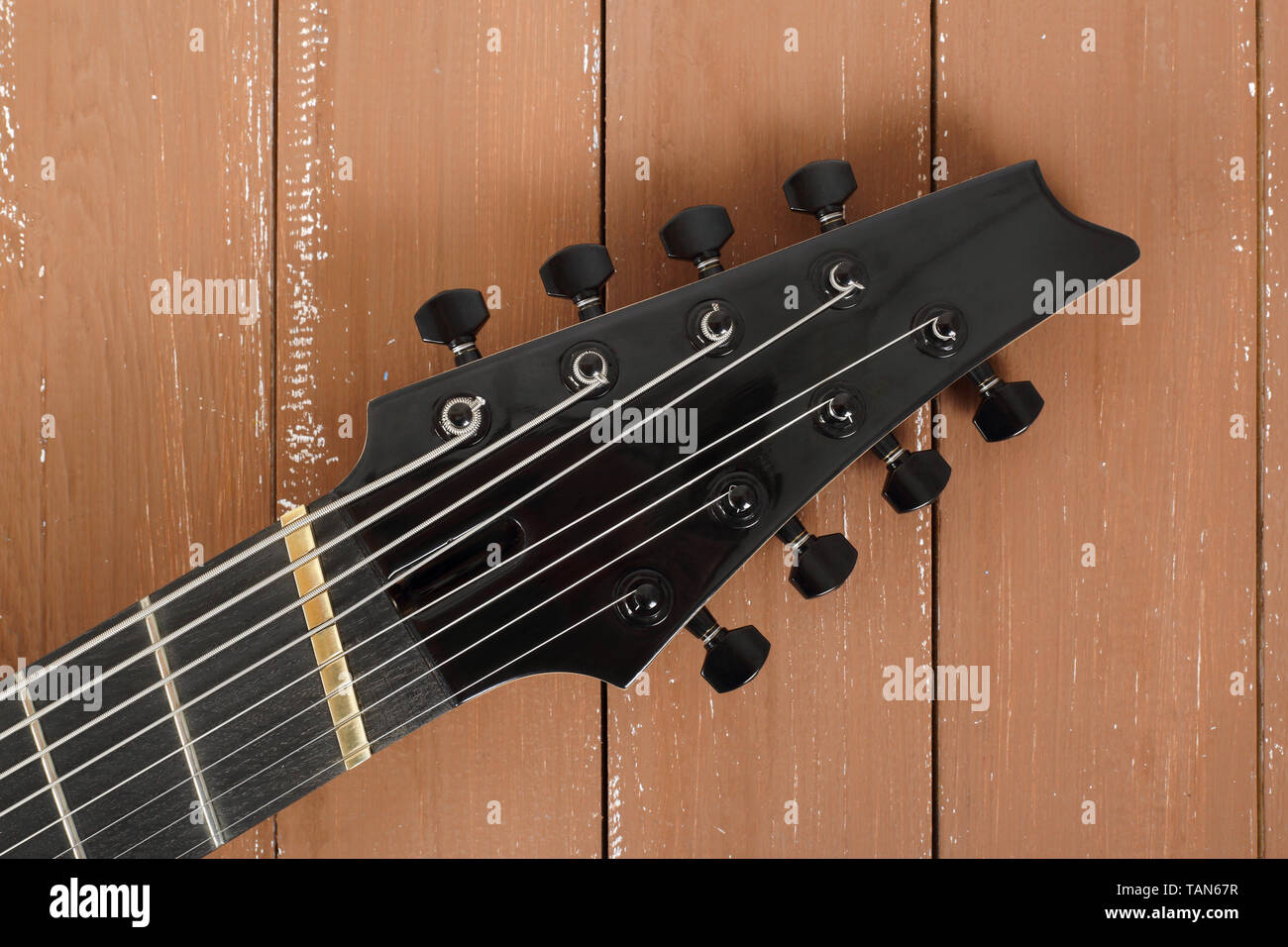 Musical instrument - headstock peghead neck tuning peg 8 string guitar on a  wood background Stock Photo - Alamy