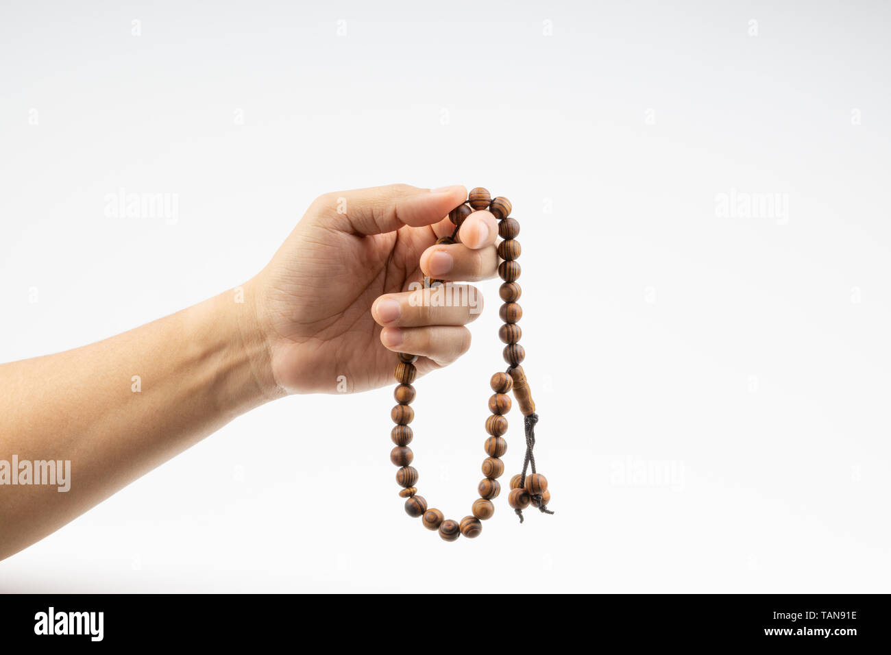 Hand holding a muslim rosary beads or Tasbih on white background. Copy ...