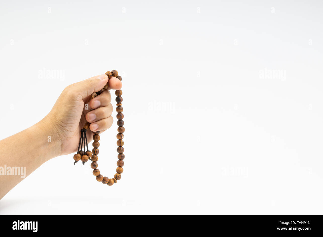 Hand holding a muslim rosary beads or Tasbih on white background. Copy ...