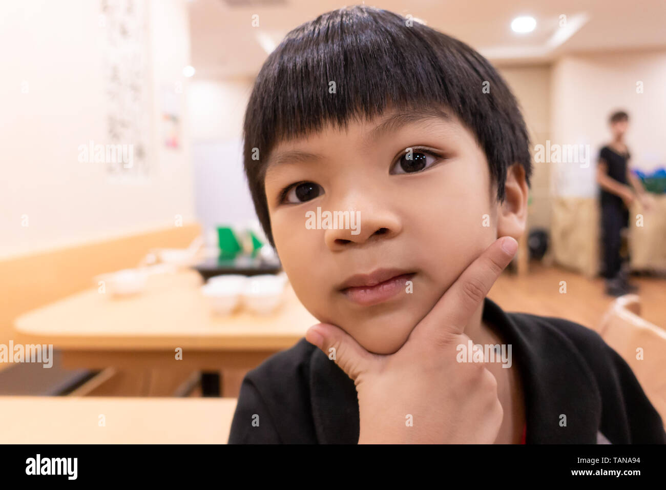 Hungry Funny child posing handsome waiting for food in restaurant. Stock Photo