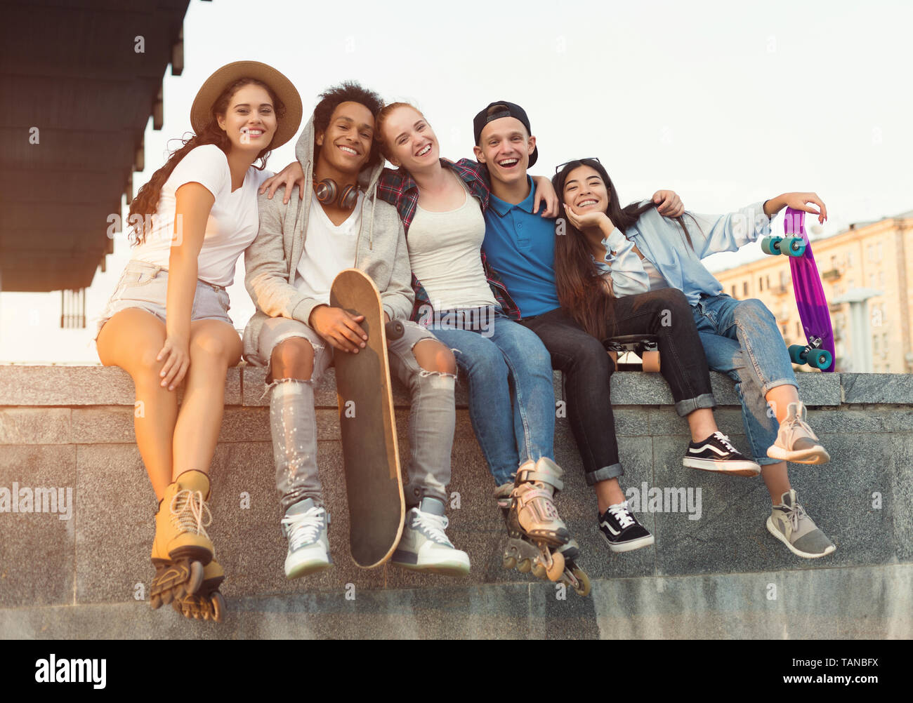 Group of active teenagers laughing together, city evening Stock Photo